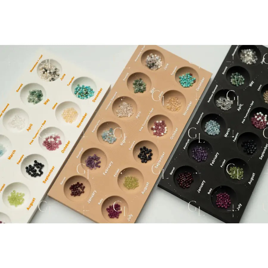 Three trays of gemstones arranged in a grid pattern on a light gray background