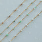 Gold chain necklaces with small beads on a light gray background