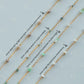 Gold fill chains with various gemstones on a light blue background