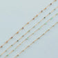 Three gold necklaces with small beads on a light blue background