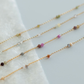 Gold necklaces with small beads on a white fabric background