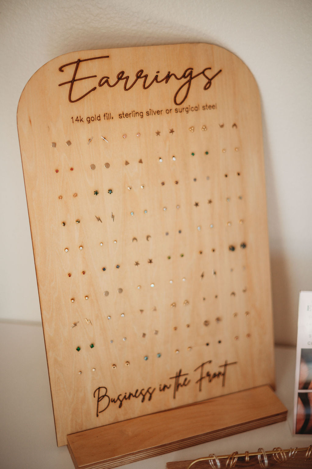 Wooden earring display board with 'Earrings' and 'Business in the Front' text on a white background.