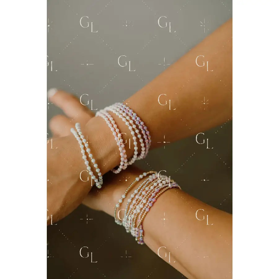 Close-up of a person's wrist wearing multiple pearl bracelets on a neutral background