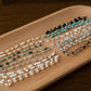 Three pearl bracelet on a wooden tray with a dark background