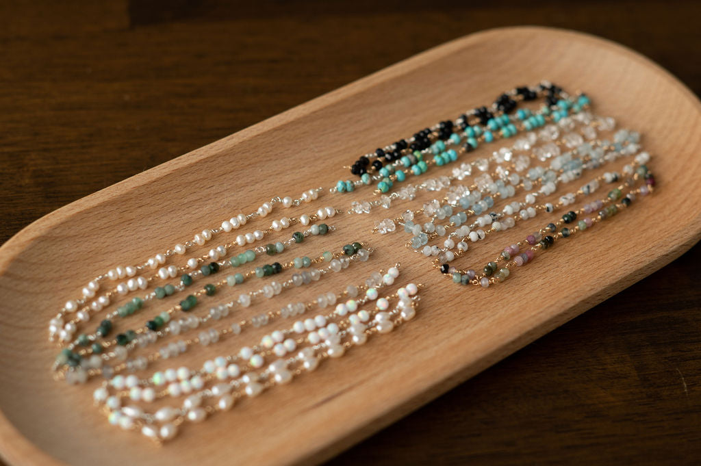 Three pearl bracelet on a wooden tray with a dark background
