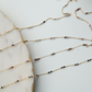 Gold chain necklace with small beads on a marble surface