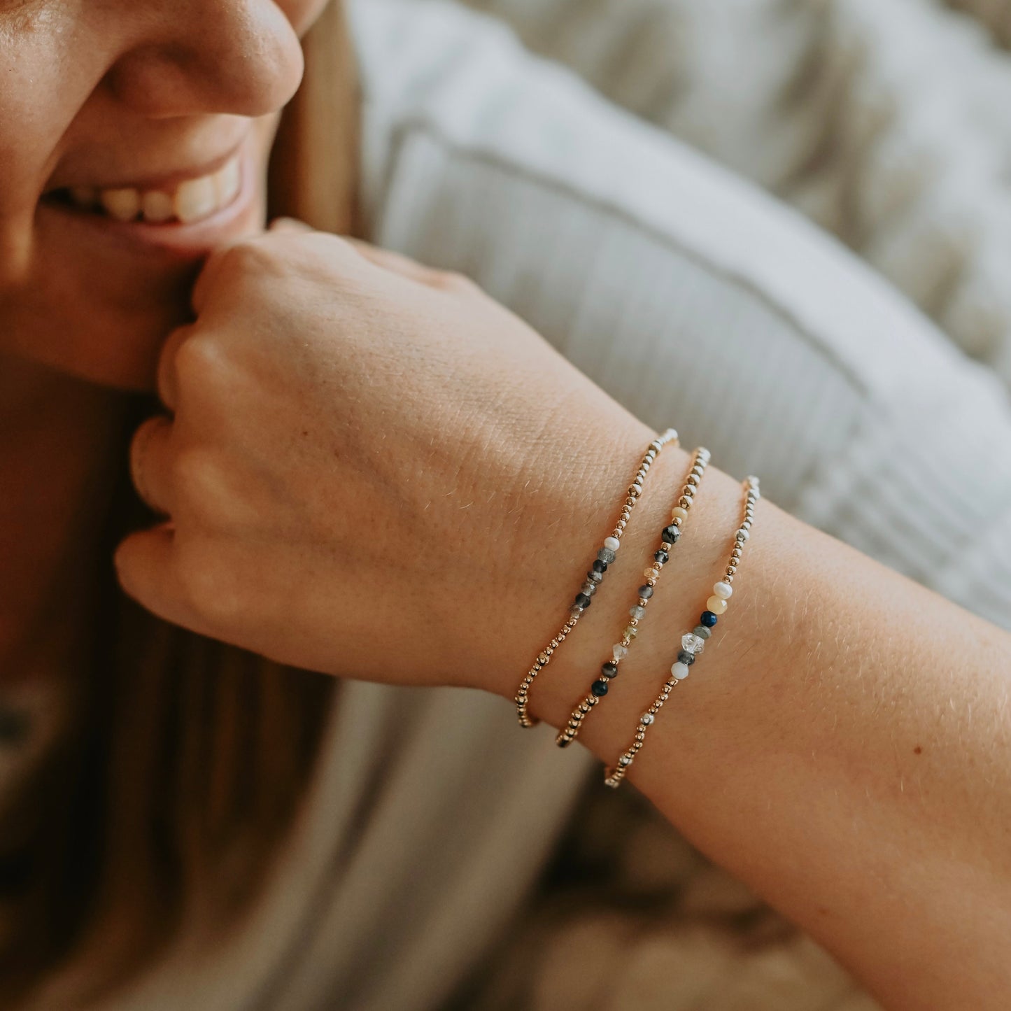 Close-up of a person wearing multiple beaded bracelets on a blurred background