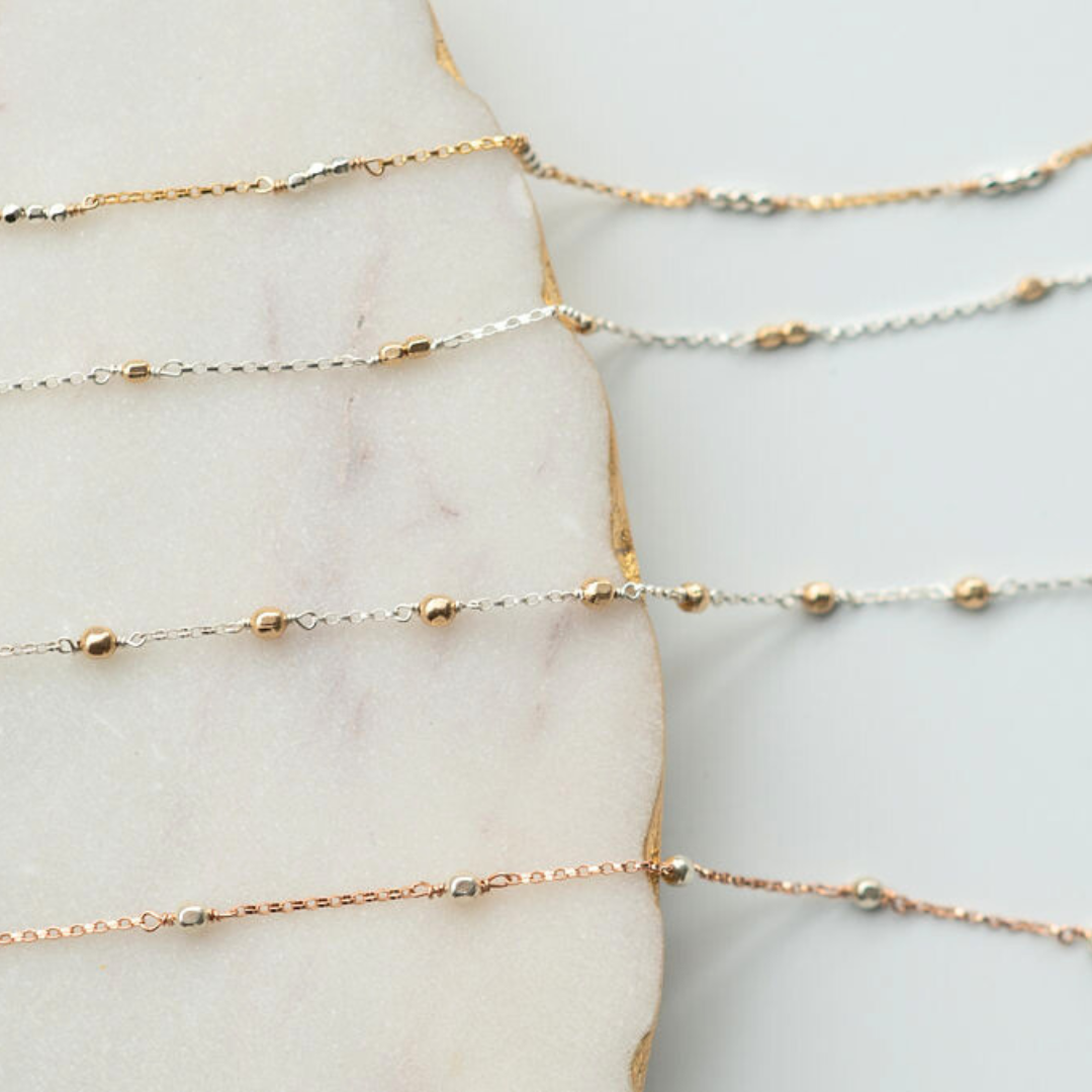 Gold and silver chain necklaces on a marble surface