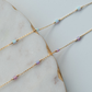 Gold chain necklace with small beads on a marble surface
