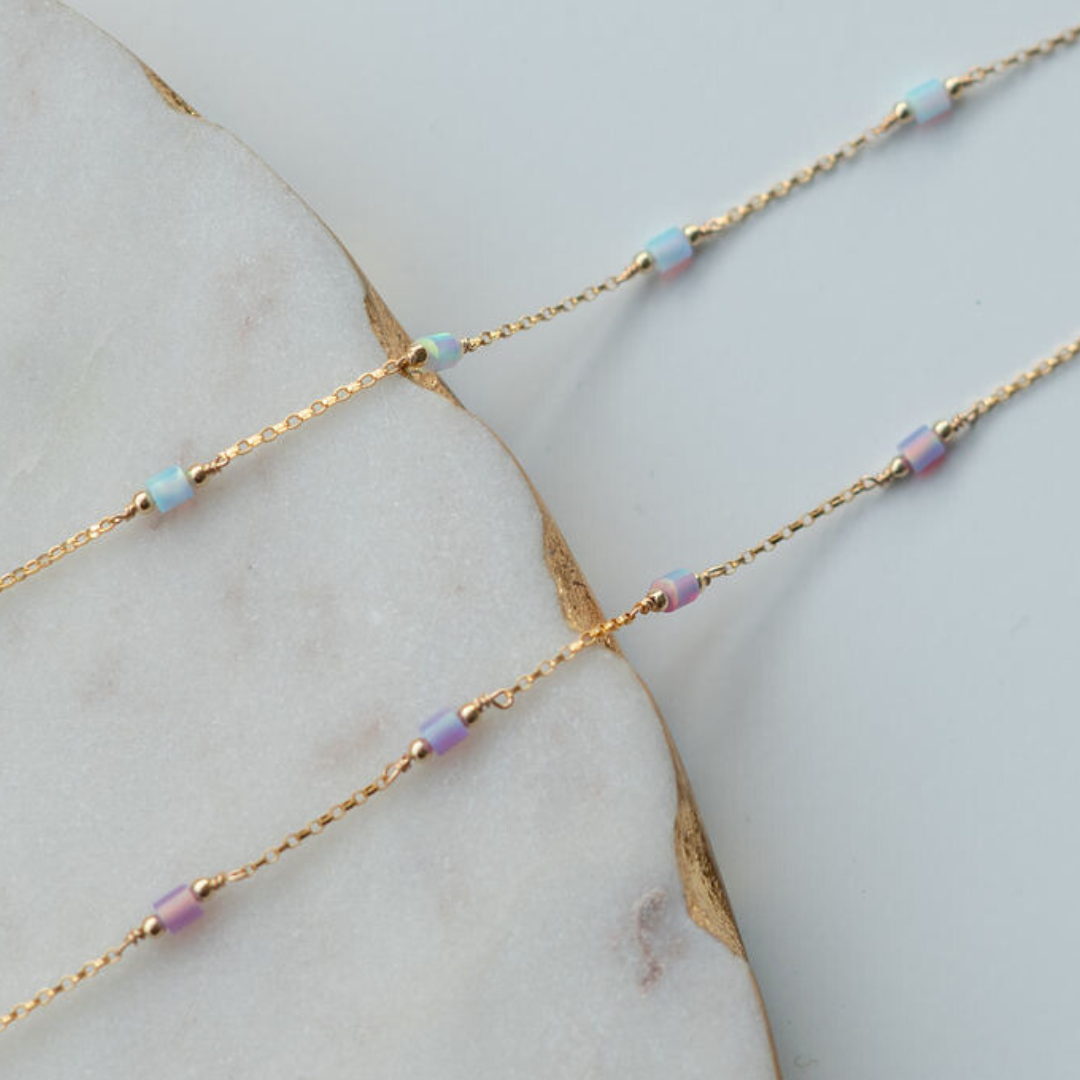 Gold chain necklace with small beads on a marble surface