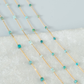 Gold chain with turquoise beads on a textured surface