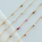 Gold chain necklaces with small colored beads on a light background