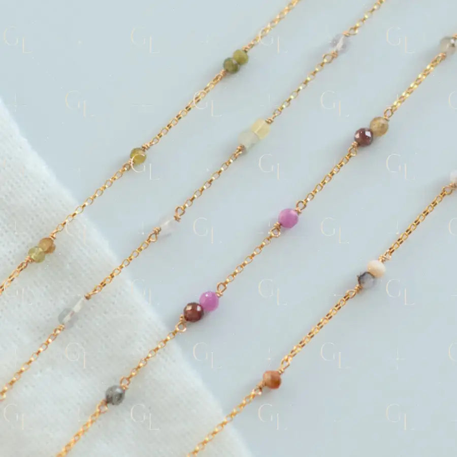 Gold chain necklaces with small colored beads on a light background