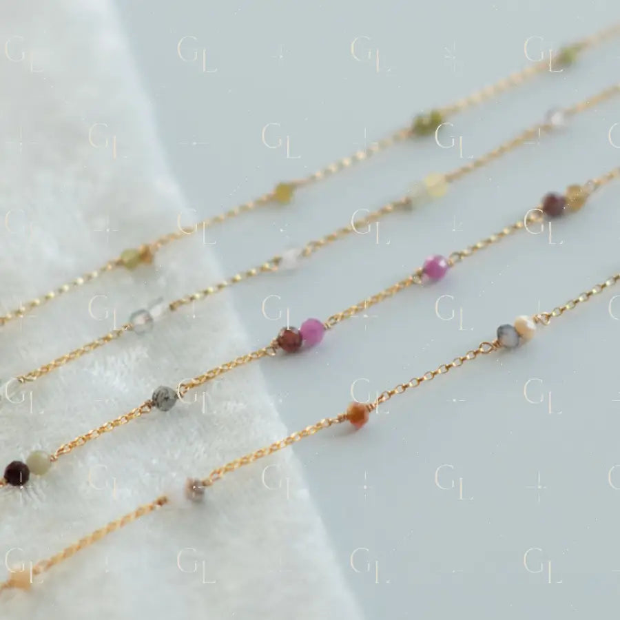 Gold necklaces with small beads on a white fabric background