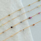 Gold fill chain with small beads on a white fabric background