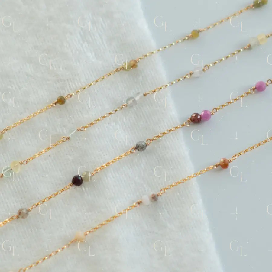 Gold fill chain with small beads on a white fabric background