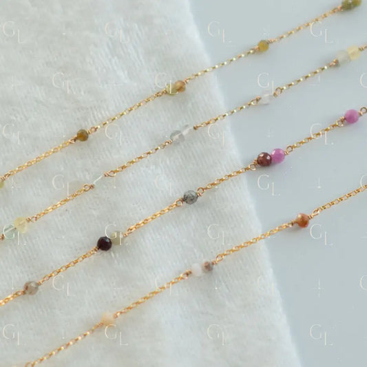 Gold fill chain with small beads on a white fabric background