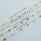 Gold chain with various gemstones on a light gray background