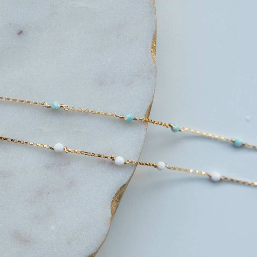 Gold chain necklace with small beads on a marble surface