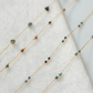 Delicate gold necklace with small beads on a white fabric background