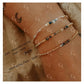 Close-up of a wrist wearing two beaded bracelets with gold and silver alternating pattern.
