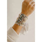 Hand wearing multiple beaded bracelets on a neutral background