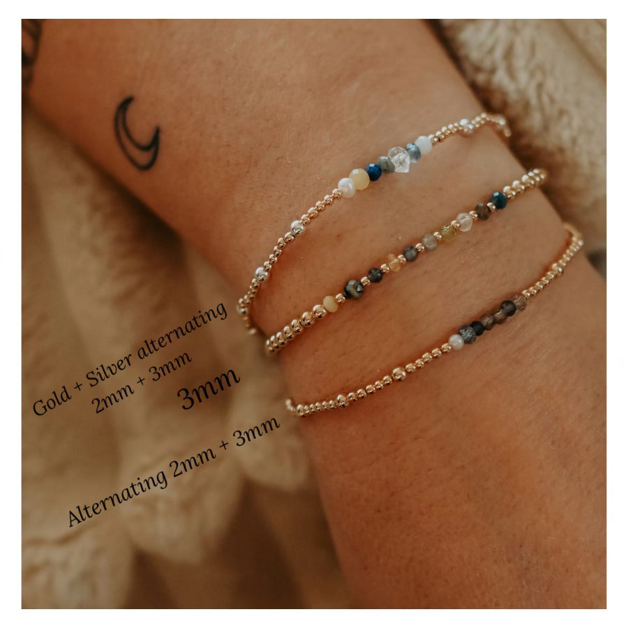 Close-up of a wrist wearing two beaded bracelets with gold and silver alternating pattern.