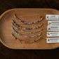 Set of beaded bracelets on a wooden tray with corresponding cards on a dark surface