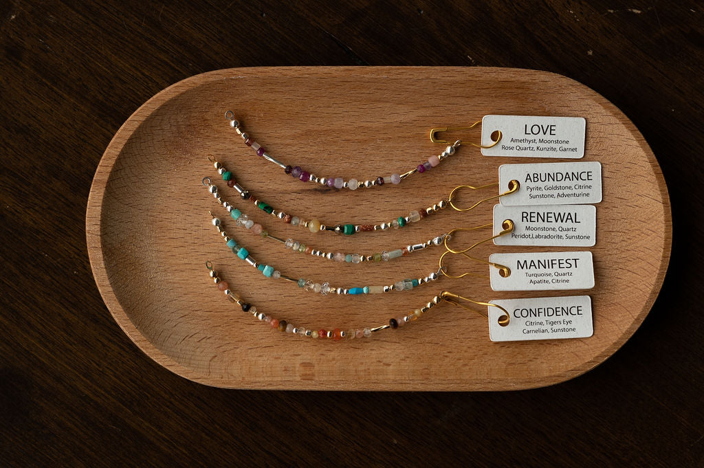 Set of beaded bracelets on a wooden tray with corresponding cards on a dark surface