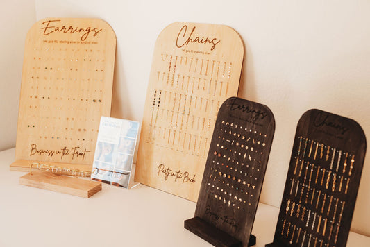 Wooden jewelry display stands with engraved text on a neutral background