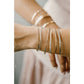 Close-up of a wrist wearing multiple silver bracelets on a neutral background Permanent Jewelry Bangle 