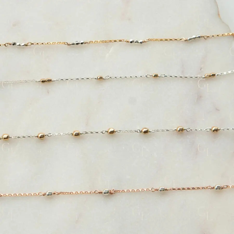 Three gold necklaces on a marble surface