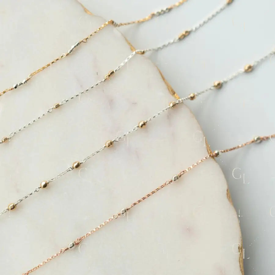 Three gold fill chain of different lengths on a marble surface