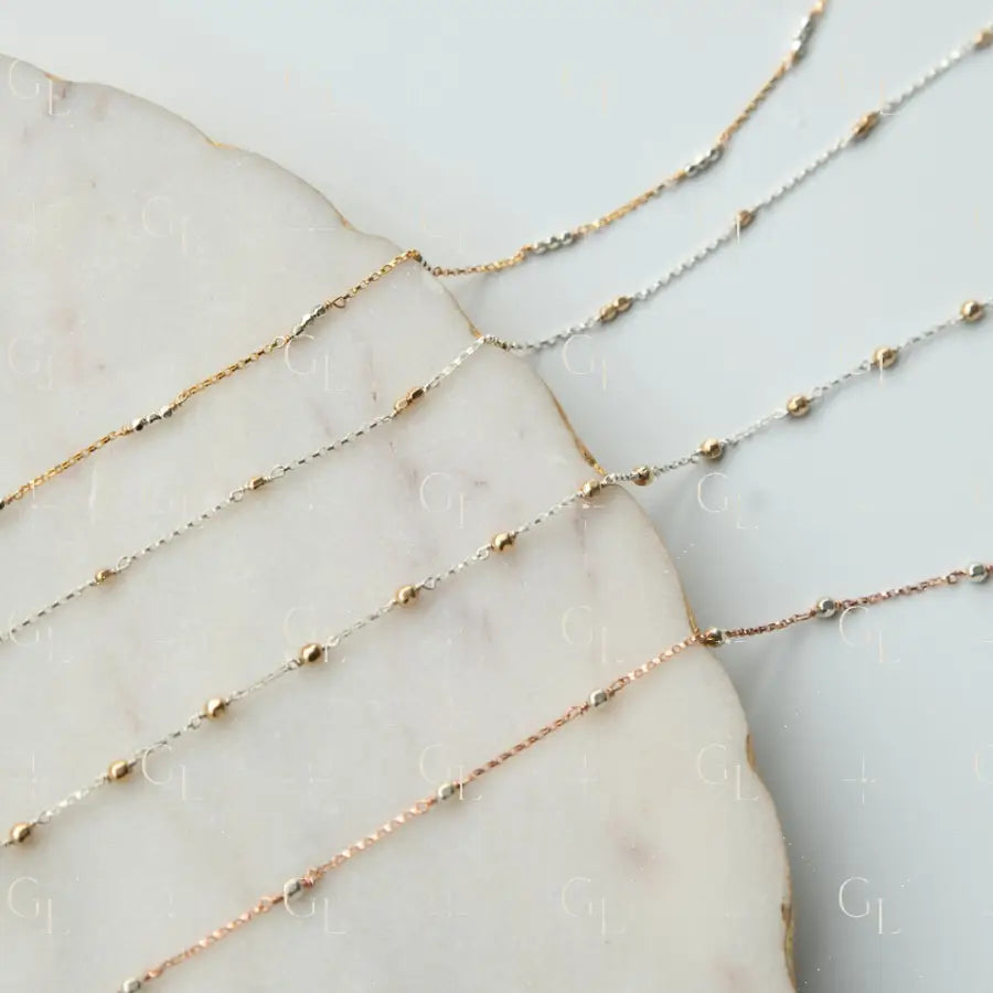 Three gold necklaces of different lengths on a marble surface