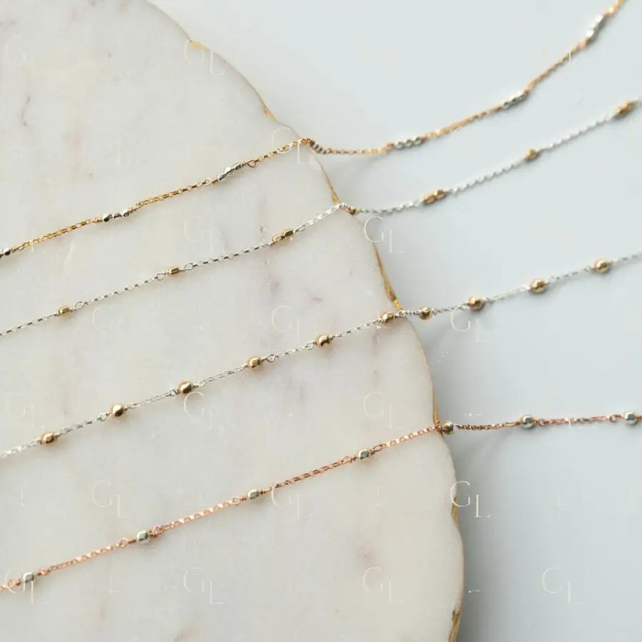 Three delicate gold fill necklaces on a marble surface
