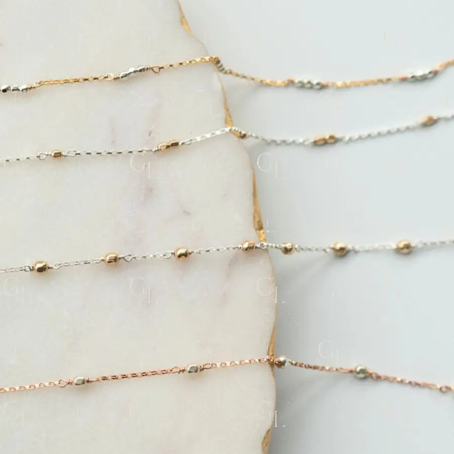 Gold and silver chain necklaces on a marble surface