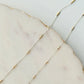 Close-up of a delicate gold and silver chain on a marble surface