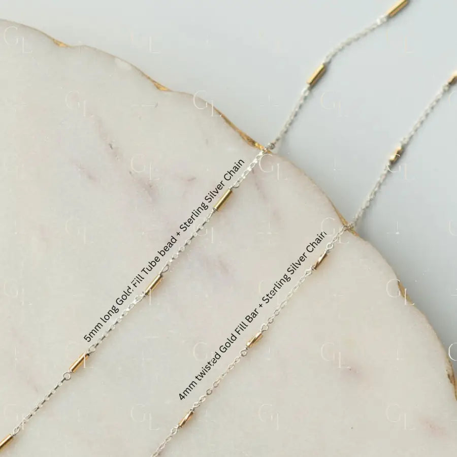 Close-up of gold fill and sterling silver chains on a marble surface
