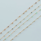 Three gold necklaces with small beads on a light blue background