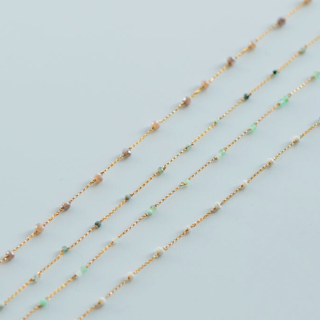 Three gold necklaces with small beads on a light blue background
