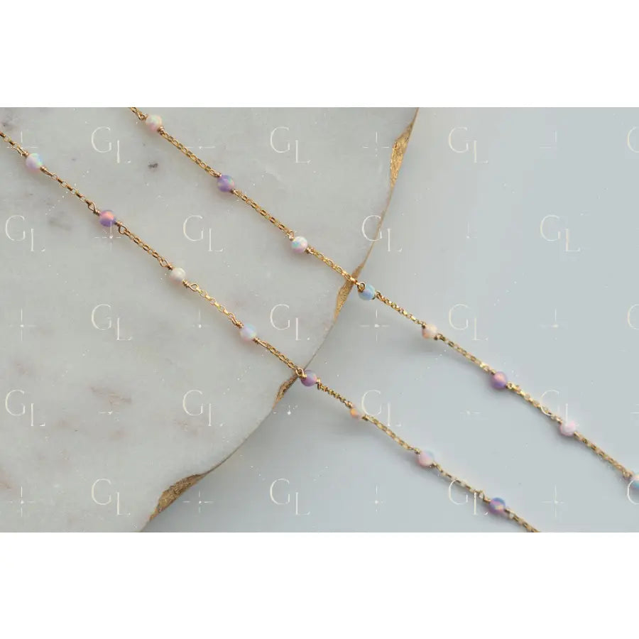 Delicate gold chain necklace with small beads on a light gray surface