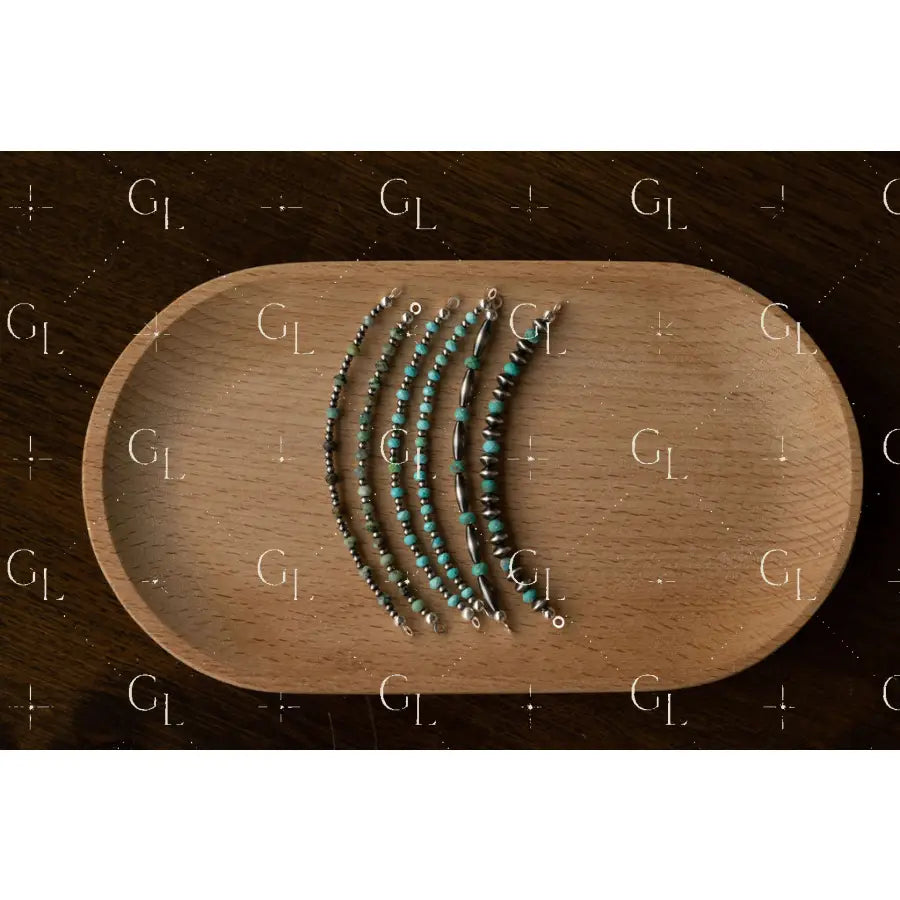 Set of silver and turquoise beaded bracelets on a wooden tray