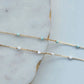 Gold chain necklace with small beads on a marble surface