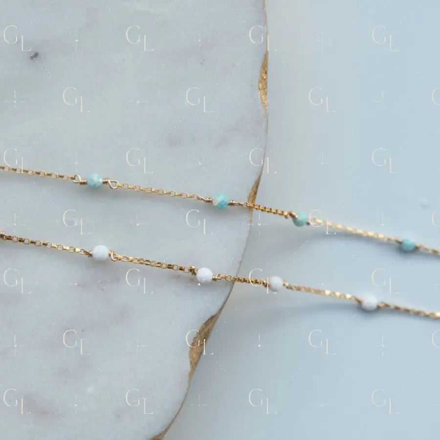 Gold chain necklace with small beads on a marble surface