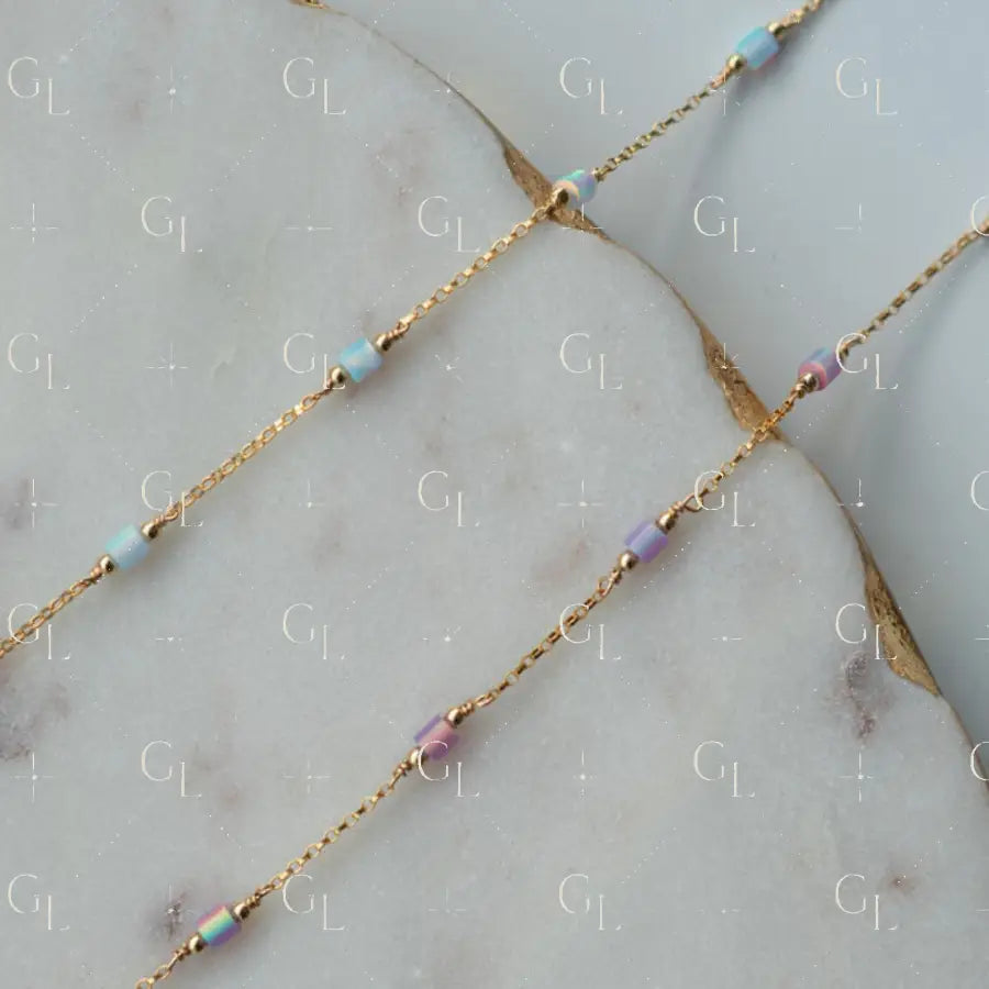 Gold chain necklace with small beads on a marble surface