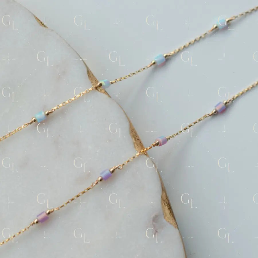Gold chain necklace with small beads on a marble surface