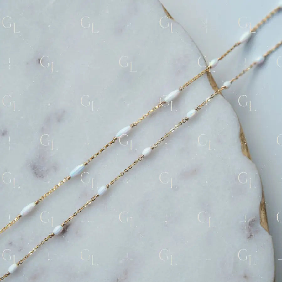 Gold fill chain necklace with opal beads on a marble surface