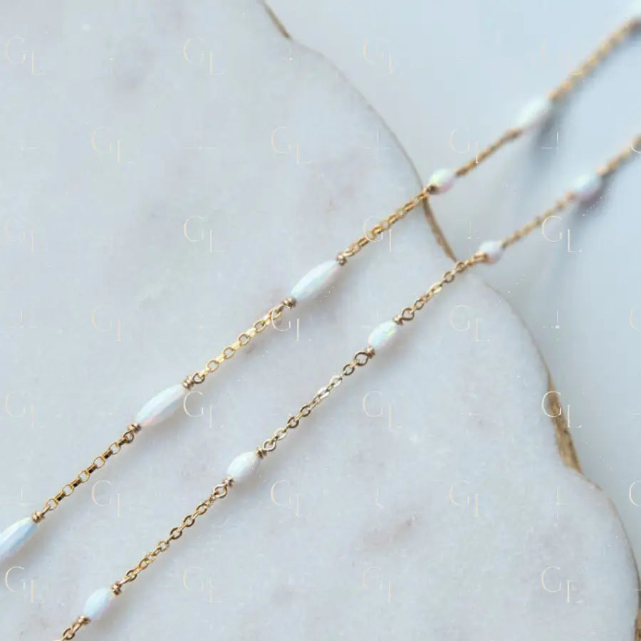 Gold chain necklace with opal on a marble surface