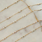 Gold chain necklaces with small beads on a marble surface