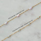 Gold chain with pink opal bar and cloud blue disc opal beads on a light gray background